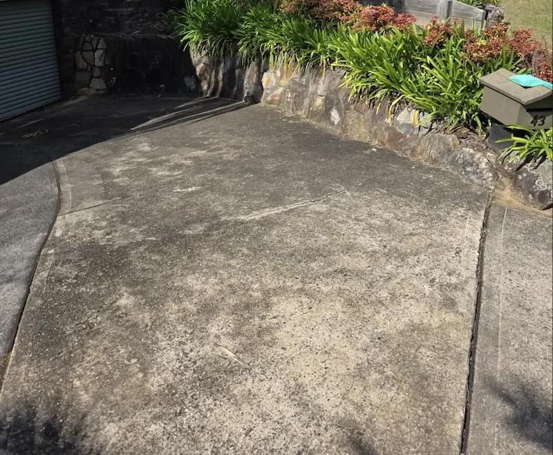 Stained concrete driveway beside garden and retaining wall in a suburban home